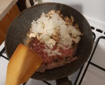 В сковороде жарятся фарш, лук и грибы